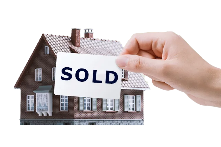 A hand holding a SOLD sign in front of a house